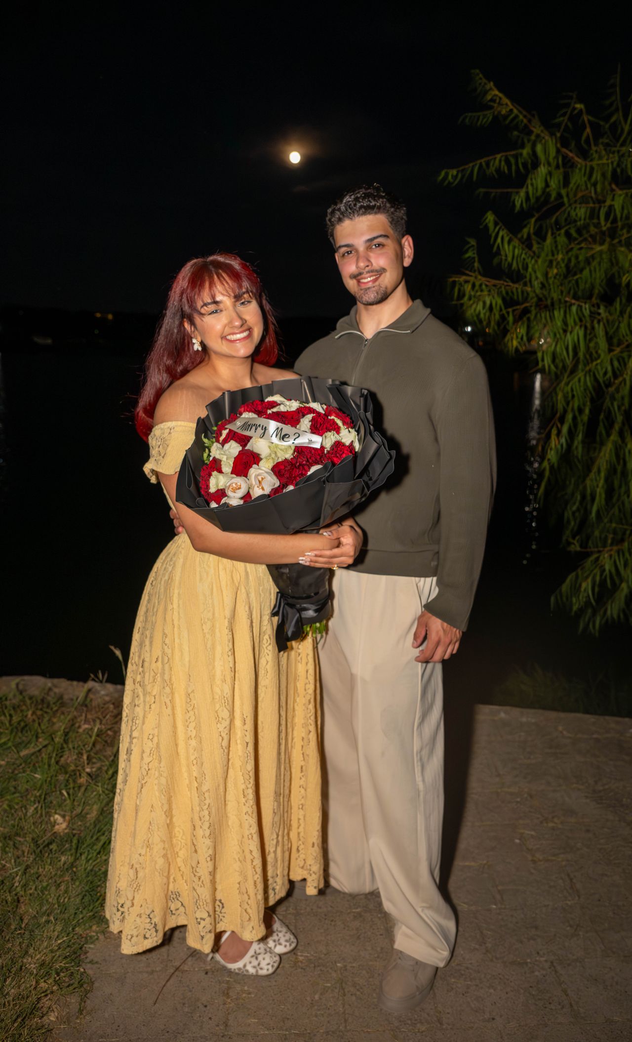 Ana and Luca stand under the moon holding the bouquet