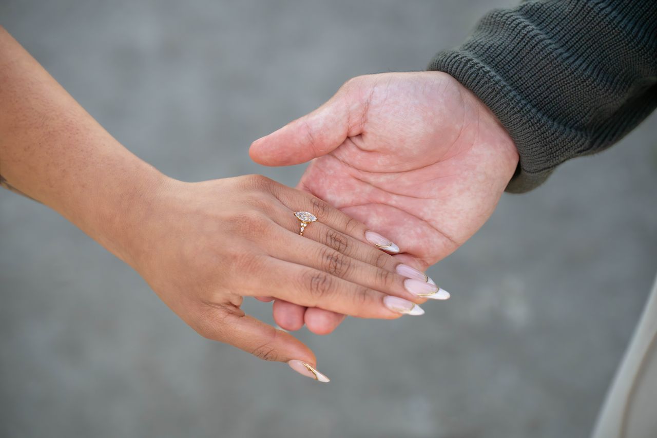 Ana's hand, wearing the ring, rests in Luca's open hand