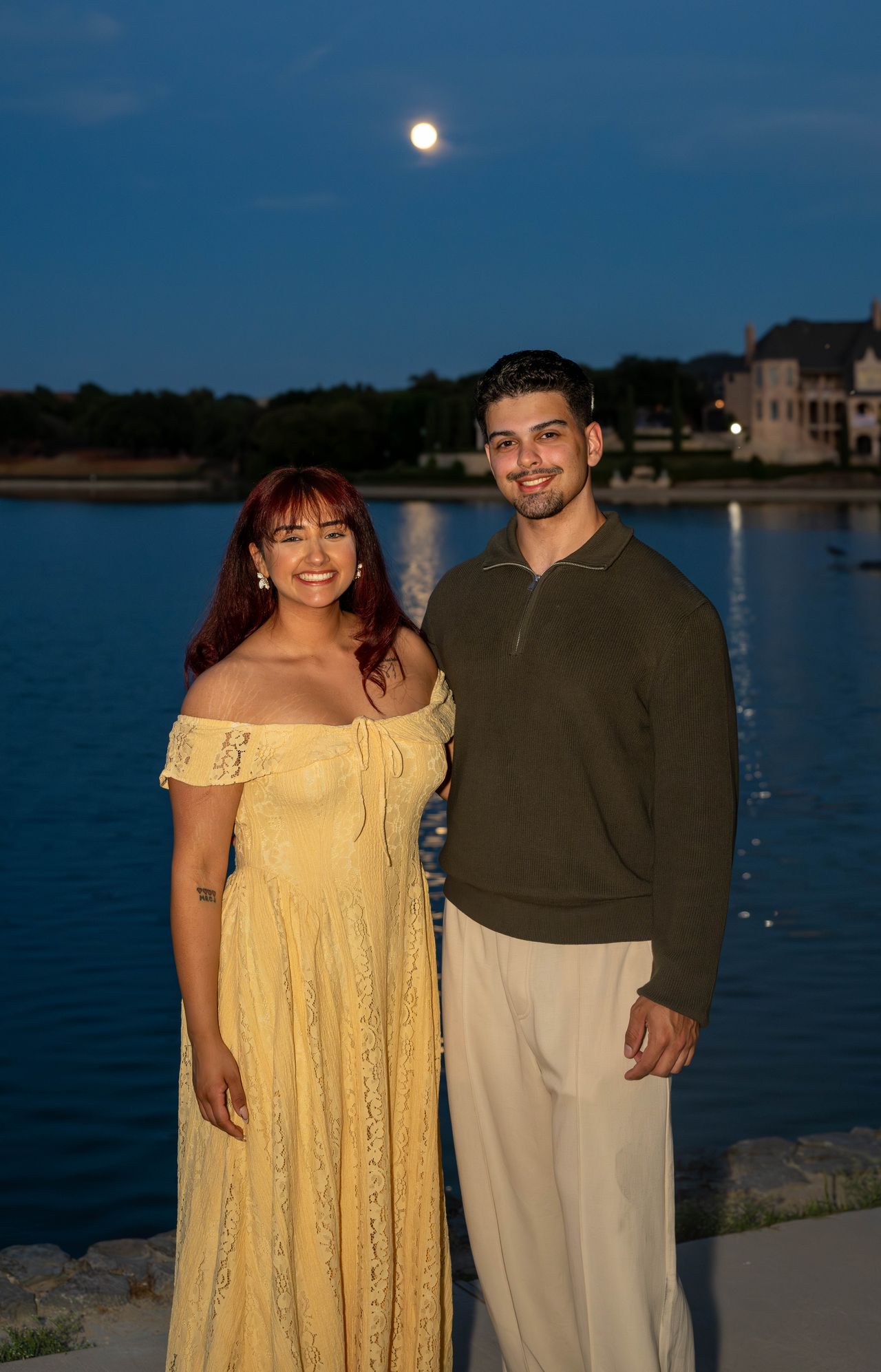 Luca and Ana stand by the lake, the moon above them