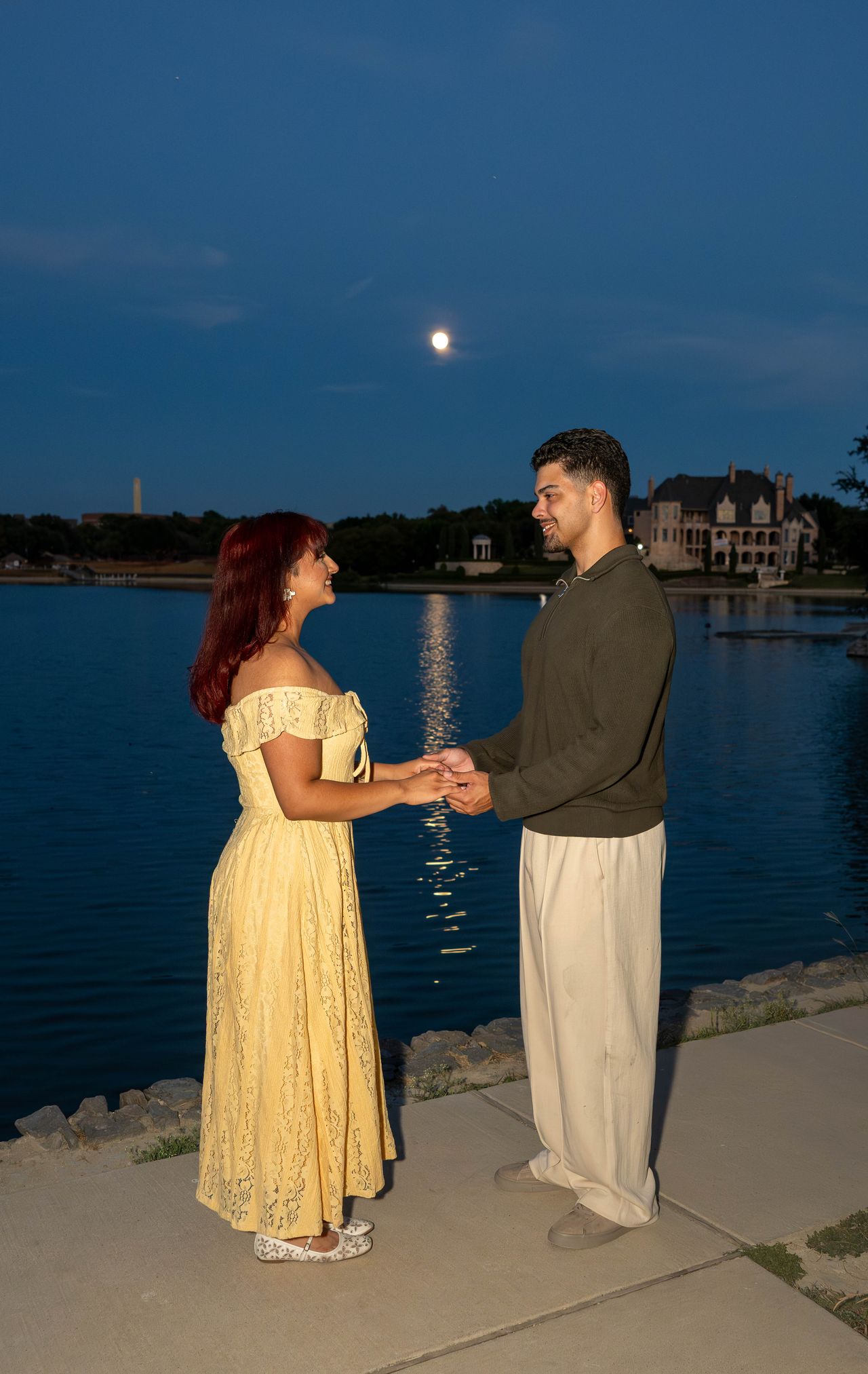Luca and Ana hold hands by the lake under the moon
