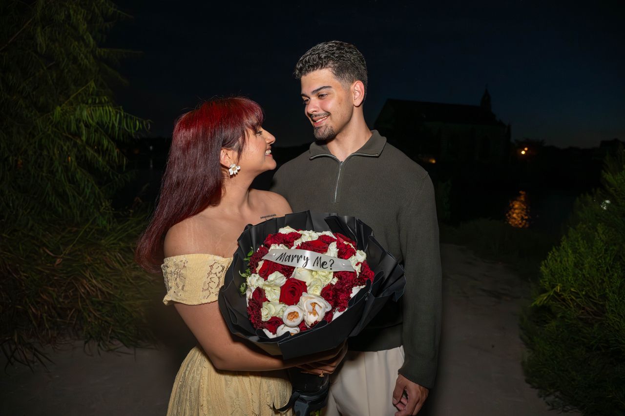 Ana looks up at Luca, holding the bouquet